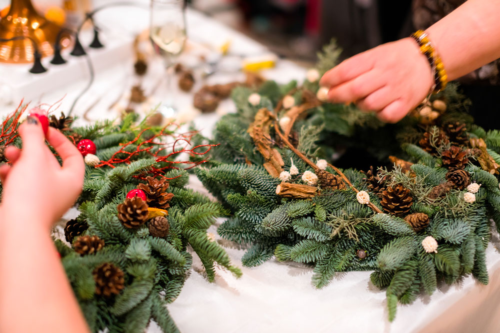 two people's hands making wreaths